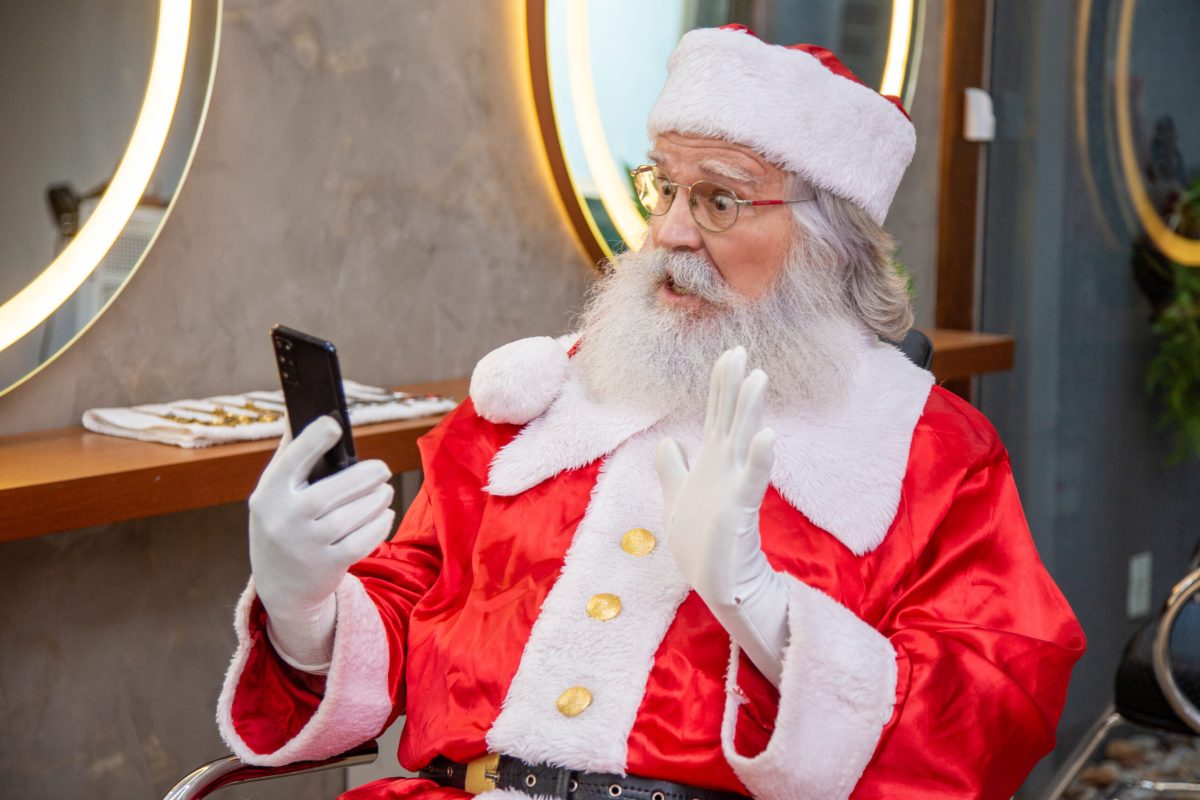 Santa Claus on the phone on a video call while getting ready in the beauty salon for Christmas Eve